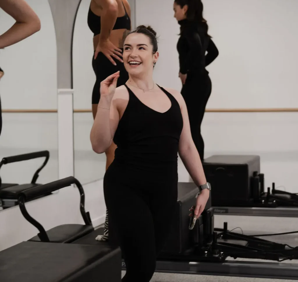 Kira Mitchell smiling warmly while encouraging clients during a Pilates session