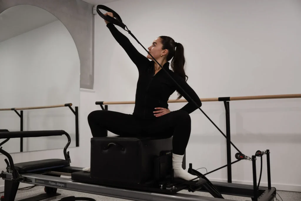Reformer pilates instructor showing proper hand and foot placement on the reformer pilates equipment