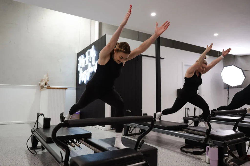 Alyce Doran standing on a reformer, demonstrating a Pilates pose with proper form