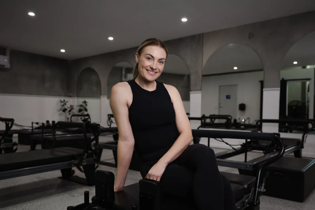 Alyce Doran, head reformer pilates instructor, posed with reformer equipment behind her at PIYO Studios